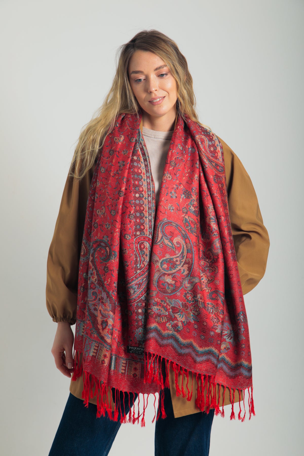 Kırmızı paisley desenli pashmina şal – kadın modeli tarafından tutulmuş, püsküllü kenarlı, geleneksel motifli şık şal
