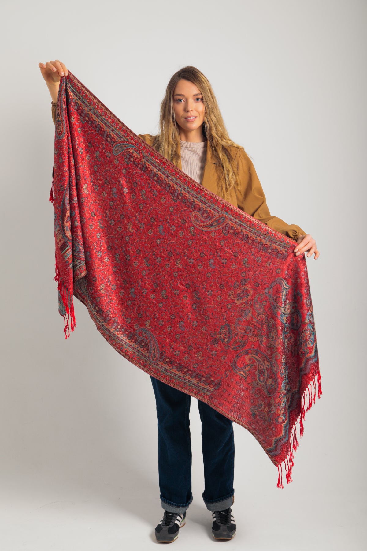 Kırmızı paisley desenli pashmina şal – kadın modeli tarafından tutulmuş, püsküllü kenarlı, geleneksel motifli şık şal