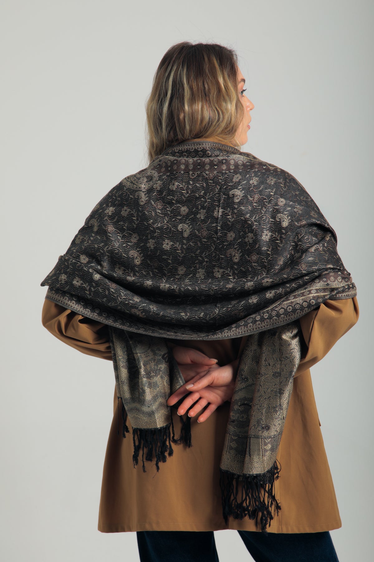 Paisley desenli siyah pashmina şal – kadın tarafından tutulmuş, püsküllü kenarlı, klasik motifli koyu renk şal modeli
