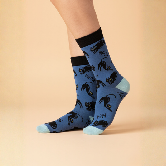 Mavi zemin üzerinde siyah kedi ve MEOW yazılı desenler bulunan, açık mavi burun-topuk ve siyah manşet detaylı erkek soket çorap.