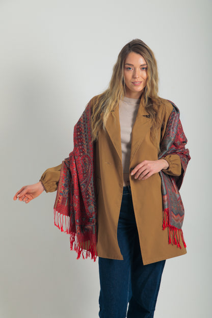 Kırmızı paisley desenli pashmina şal – kadın modeli tarafından tutulmuş, püsküllü kenarlı, geleneksel motifli şık şal