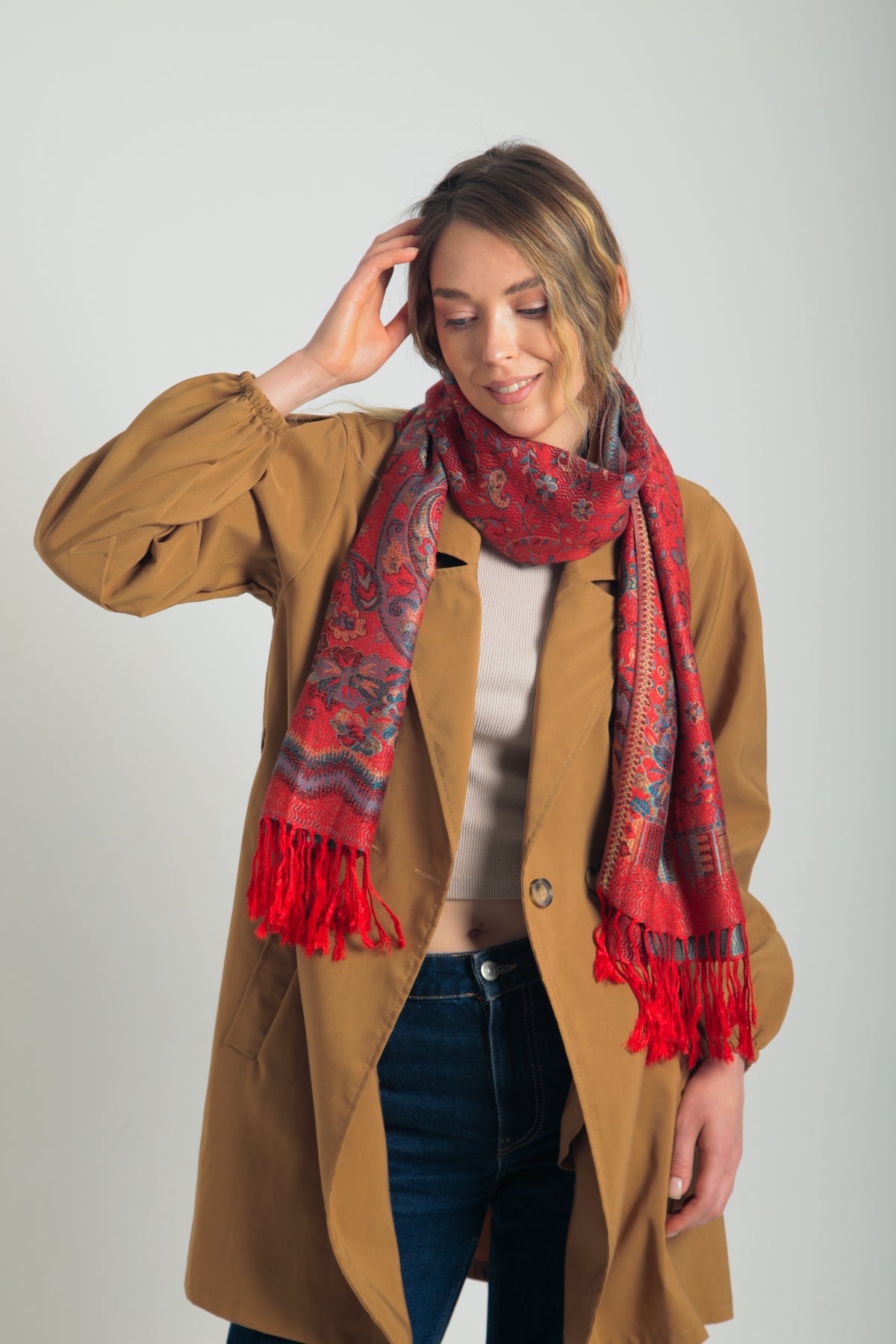 Kırmızı paisley desenli pashmina şal – kadın modeli tarafından tutulmuş, püsküllü kenarlı, geleneksel motifli şık şal