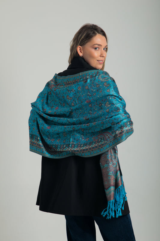 Paisley desenli turkuaz pashmina şal – omzuna almış kadın modeli, canlı renkli, püsküllü ve geleneksel motifli şal
